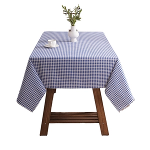 Blue and white checkered tablecloth with lace edges on a wooden dining table