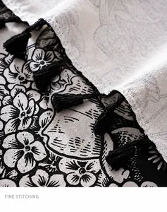 Detailed close-up of French vintage floral linen fabric with fine stitching and black fringe