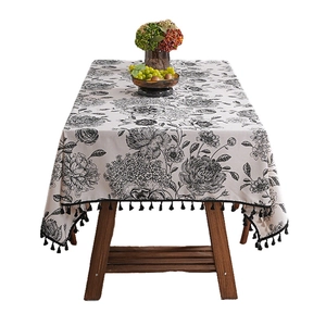 French vintage linen tablecloth with black floral patterns and tassel edges on white base