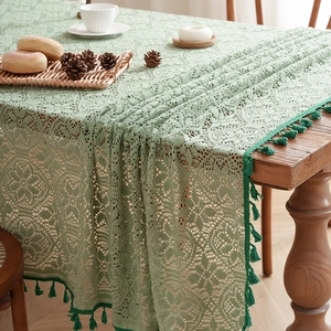 French vintage light green lace tablecloth with elegant dark green tassels on wooden table
