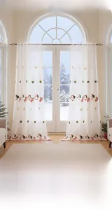 Detail of white sheer curtain with embroidered Santa Claus and Christmas patterns