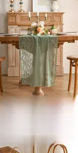 Detail of light green hollow lace table runner with floral patterns and wavy edges