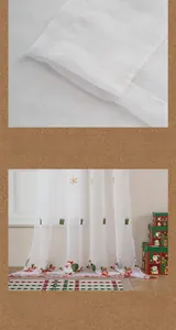 Detail of Christmas sheer curtain with festive Santa, snowflake embroidery and pom-pom edge