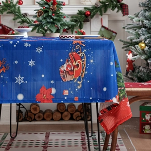 Blue Christmas tablecloth with Santa Claus sleigh and poinsettia prints on a festive table