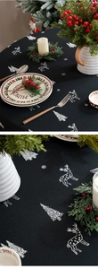 Detailed macro view of black linen Christmas tablecloth with embroidered deer and tree patterns