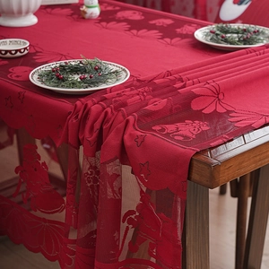 Red Christmas lace tablecloth featuring bell and Santa patterns on a rustic wooden dining table