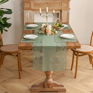 Green lace table runner set with floral hollow pattern on a rustic wooden table
