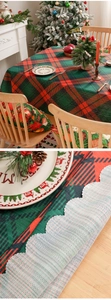 Detail of red and green plaid Christmas tablecloth with scalloped edges and textured backing