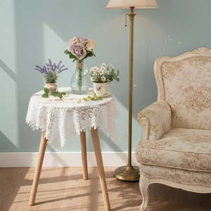 French vintage white lace round tablecloth with hollow floral pattern on wooden coffee table