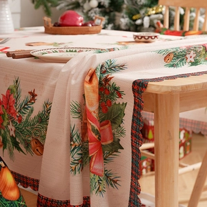 Christmas tablecloth with pine branches and red berries pattern on a rustic wooden table
