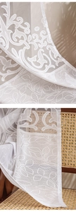Macro detail of French white lace curtain showing floral embroidery and light mesh texture