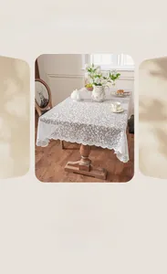 Detailed view of white floral lace tablecloth with jacquard patterns and scalloped edges