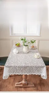 Detail of white hollow lace tablecloth with floral patterns and wavy edges on a wooden table