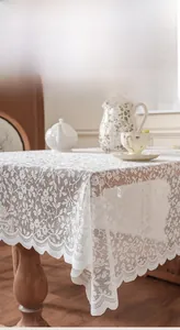 Close-up of white lace tablecloth featuring delicate floral hollow patterns and wavy edges