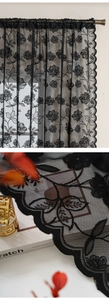 Detail of black floral lace curtain showing intricate mesh texture and scalloped wavy edges