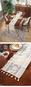 Detail of white lace table runner with floral bird embroidery and decorative tassels