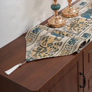Luxurious elephant stripe table runner with tassels on a dark wood surface