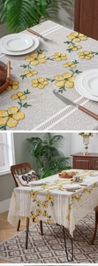Detail shot of yellow floral embroidery and hollow lace border on a gray tablecloth