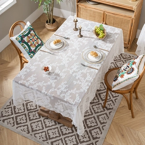 Elegant white lace tablecloth with floral patterns draped over a wooden dining table