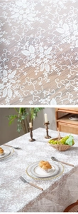 Close-up of white floral lace tablecloth with intricate mesh crochet and wavy edge detail