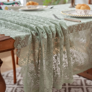 Light green floral lace table runner with scalloped edges on a wooden dining table