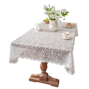 White floral hollow lace tablecloth with elegant wavy edges on a vintage wood table