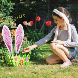 Osterdeko-Set mit Filzhasenkorb und rosa karierten Ohren auf einer sonnigen Wiese