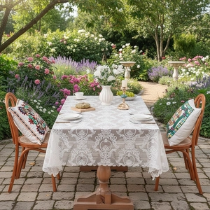 Elegant white lace tablecloth with damask patterns on an outdoor wooden dining table