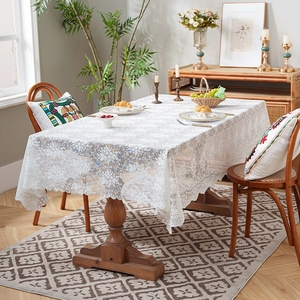 Elegant white lace tablecloth with floral patterns on a rectangular wooden dining table