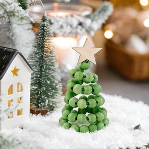 Close-up of green wooden bead Christmas tree with star topper on snowy background