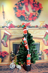 Three Santa Claus figures climbing on a rope hanging as Christmas tree decoration