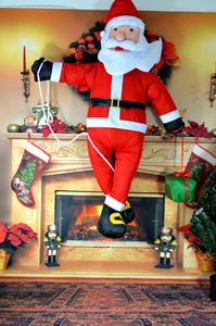 Climbing Santa Claus doll on a rope with gift box near fireplace Christmas decor