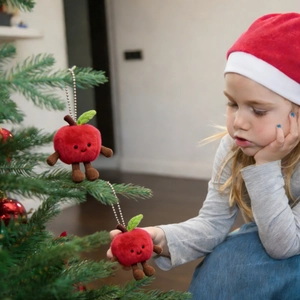 Plush Christmas apple ornament with smiley face hanging on a festive tree branch