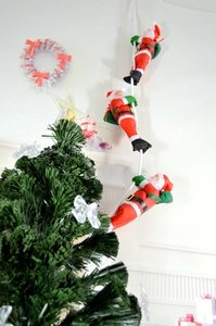 Detailed view of three Santa Claus figures climbing a white rope for festive decoration