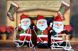 Three plush Santa Claus figurines on rope ladders with festive reindeer patterns