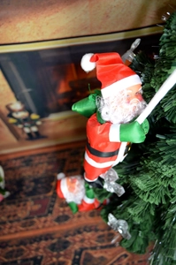 Détail de poupées Père Noël grimpant avec sacs verts en décoration de sapin de Noël