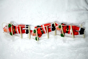 Detailed view of three Santa Claus climbing a 25cm wooden rope ladder on snowy background