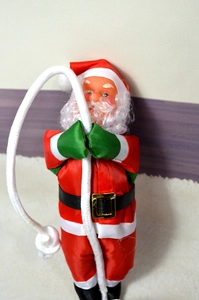Détail du Père Noël de 25cm grimpant avec costume rouge et gants verts sur corde