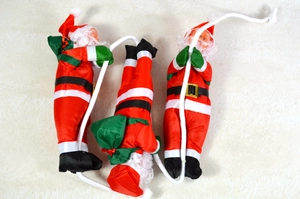 Close-up of three Santa Claus plush dolls climbing a white cotton rope for tree decoration