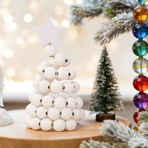Close-up of a white wooden bead Christmas tree with a star topper on a rustic base