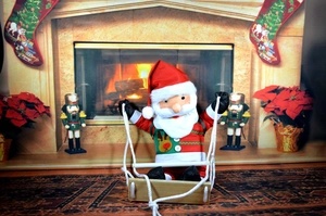 Detail of Santa plush toy in striped sweater hanging on a wooden swing decoration