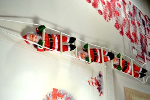 Detailed view of three Santa Claus figures climbing a white rope ladder for Christmas decor
