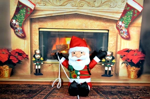 Detail of hanging Santa Claus doll with reindeer chest plate and rope on festive fireplace