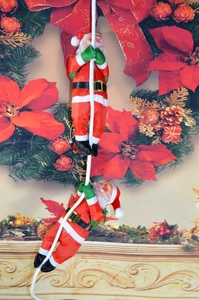 Détail de deux figurines du Père Noël grimpant sur une corde pour décoration murale