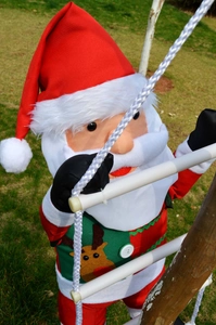 Detail of Santa Claus figure with reindeer embroidery climbing a white rope ladder outdoors