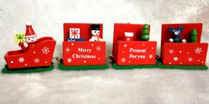 Close-up of a 4-section red and green wooden Christmas train on a snowy white surface