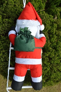 Detailed view of outdoor Santa Claus climbing a white rope ladder with green gift bag