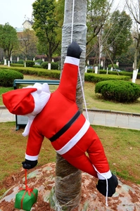 Close-up of a Santa Claus doll climbing a white rope for outdoor Christmas tree decoration
