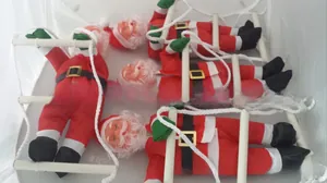 Close-up of three decorative Santas climbing a soft ladder with green gift bags