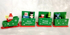 Detail of green wooden 4-section Christmas train set with festive figurines on faux fur snow